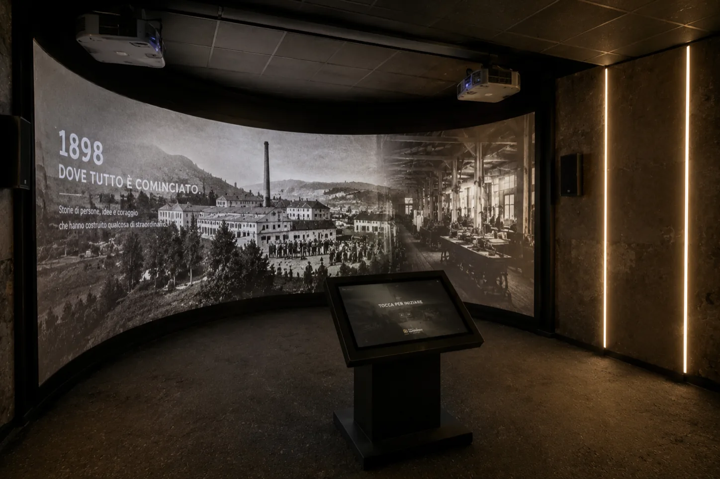 Story Room de museo con relato histórico proyectado sobre pantalla curva y quiosco interactivo